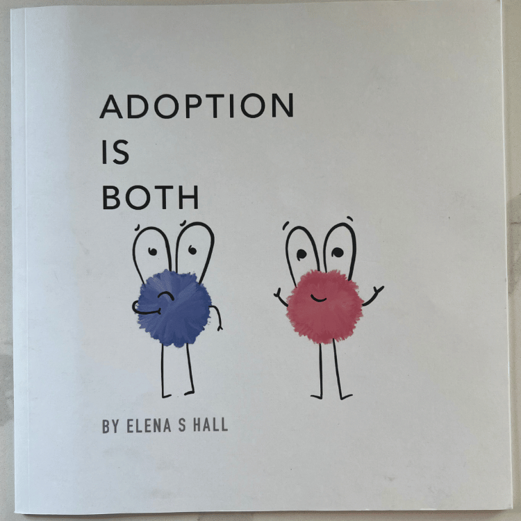 A photograph of the book cover of Adoption Is Both sitting on a white counter top. The background of the cover is all white. With blue puff ball with eyes, legs, arms, and sad face on the left. A red puff ball with eyes, legs, arms, and a happy face no the right. The words "ADOPTION IS BOTH" towards the top to the left and the words "BY ELENA S HALL" at the bottom left.